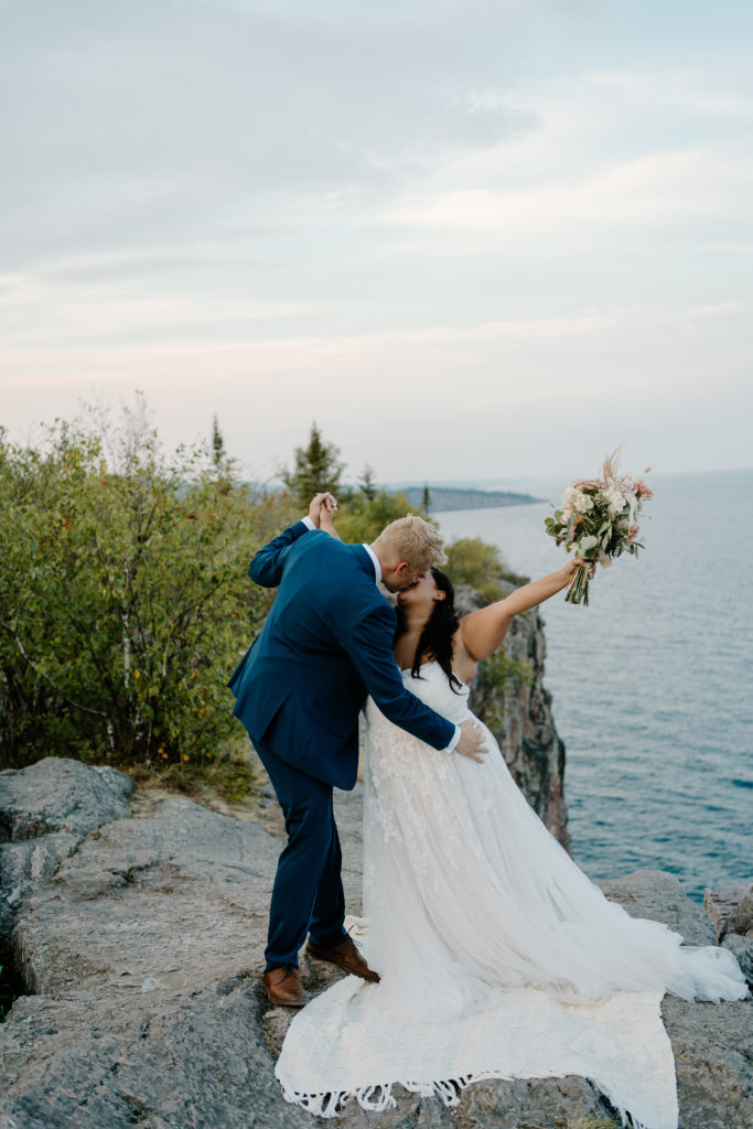 A groom kissing his bride as they celebrate eloping on the north shore of Lake Superior.