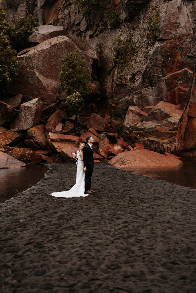 A couple posing on Black Sand Beach during their elopement on the north shore of Lake Superior.